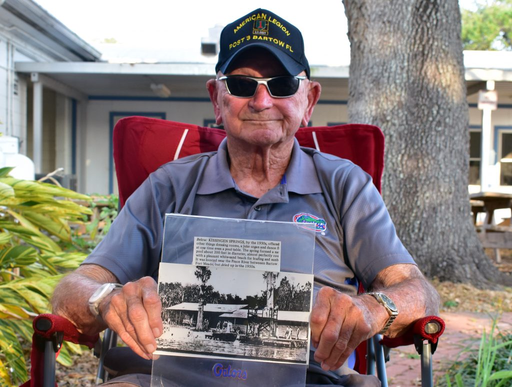 Ben Jackson, 93, holds up a sign of a photo of the Kissengen Spring recreation area in Polk County on Feb. 24, 2023.