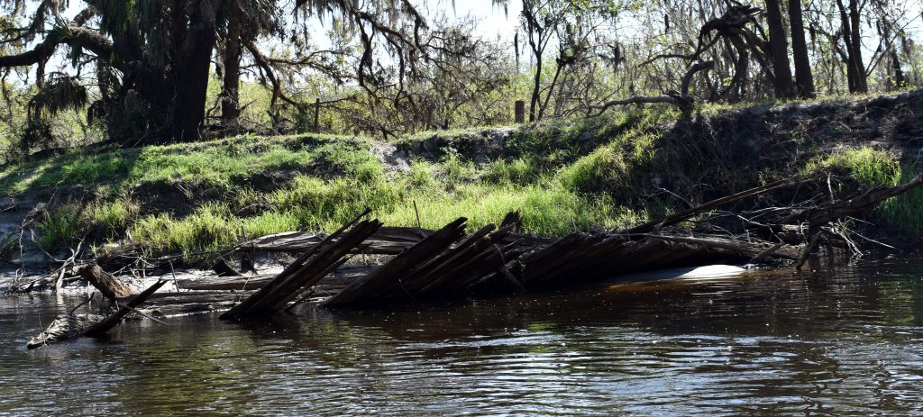 A broken dock lies alongside the Peace River in Arcadia, Fla. Feb. 24, 2023.