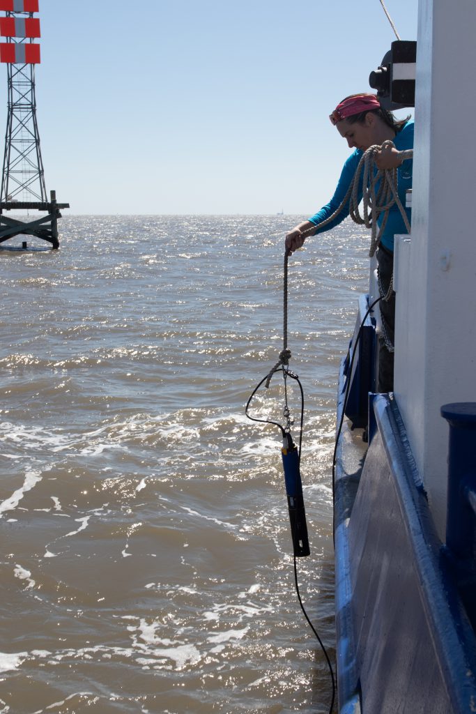 Cassandra Glaspie leans over the Acadiana to put a conductivity, temperature and depth sensor into the water in Terrebonne Bay, La., Wednesday, March 15. The sensor measures essential elements of the water. (Jocelyn Heimsoth/Missourian)