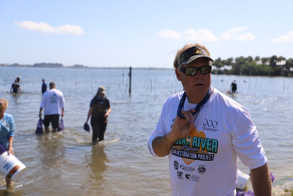 Blair Wiggins stands in shallow waters with a team of volunteers behind him. 