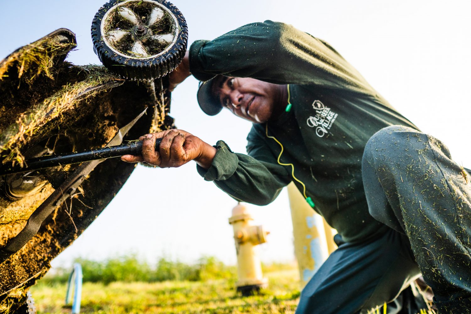 Piwi Rios scrapes his lawnmower clean after an early-morning job. The Guatemala native moved to the U.S. at 21 and began work picking tomatoes. He now works a stable landscaping job that allowed the family to move into their first home. (Justin Bright/WUFT News)