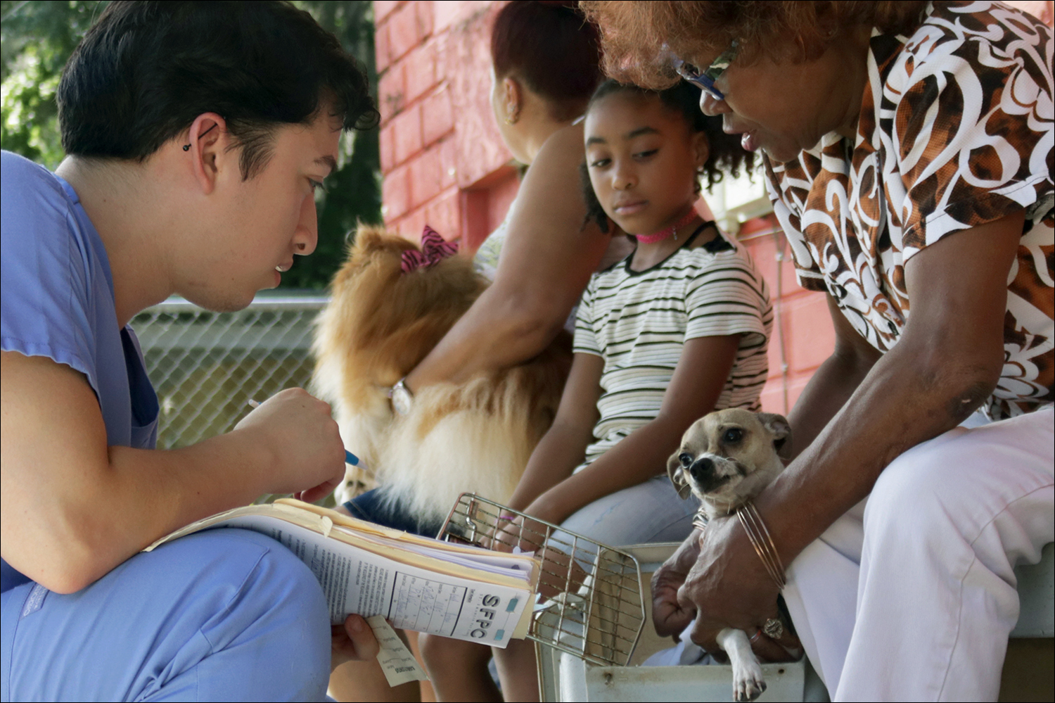 David Rodriguez discusses the health of Vera Matthew's dog, Nate, as she waits outside to be seen by a vet. (Kaitlin Hall/WUFT News)