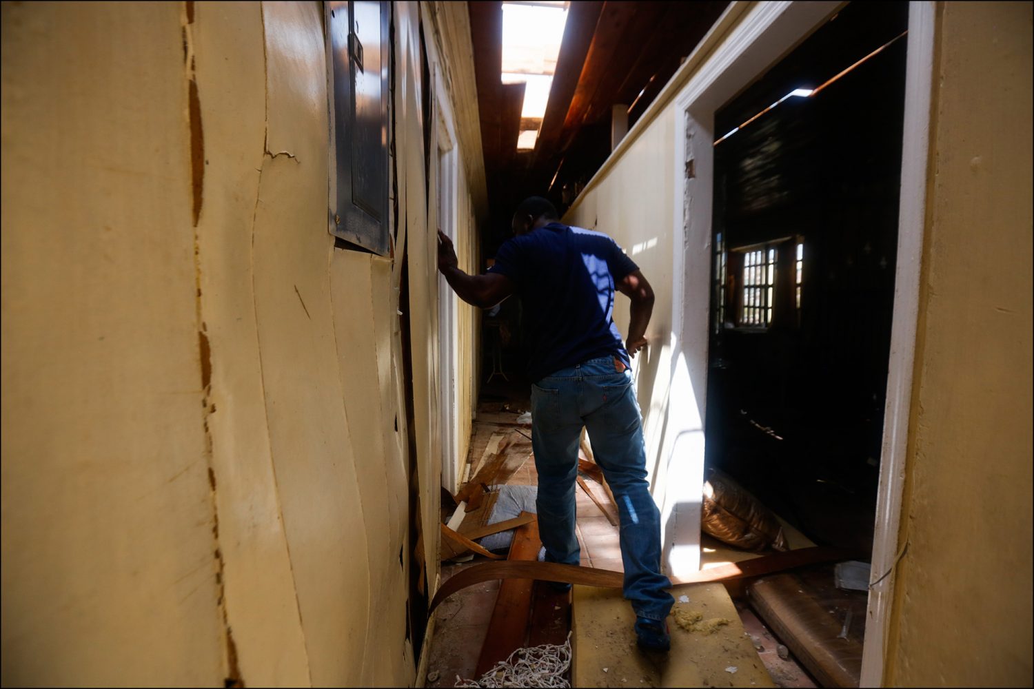 Traz Nixon steps over debris in his home while assessing the damage from Hurricane Dorian in Marsh Harbor, Abaco on Sept. 19, 2019.