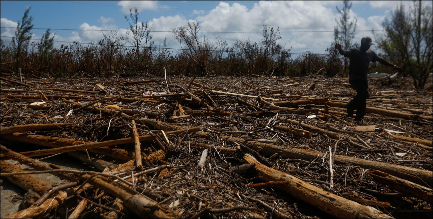 Charles Johnson walks across the fallen trees covering Elizabeth Road in the Queen's Cove neighborhood of Freeport, Grand Bahama on Sept. 17, 2019.