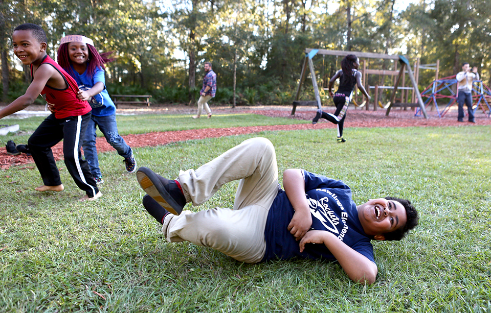 Dashawn rolls in the grass on the playground of Kids Count, his safe place. The Rawlings elementary student will graduate from the program next year. (Emma Green/WUFT News)