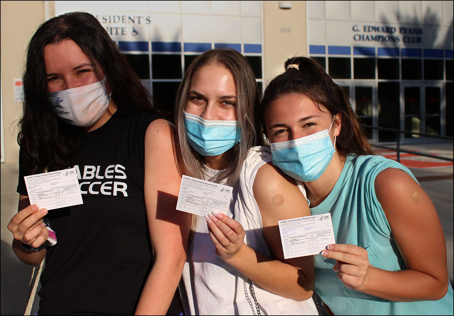 Juliana Balladares (left), Lauren Tope (middle) and Rachel Stevenson (right) show off their COVID-19 vaccination shot. They also hold up their appointment card for the second shot.
