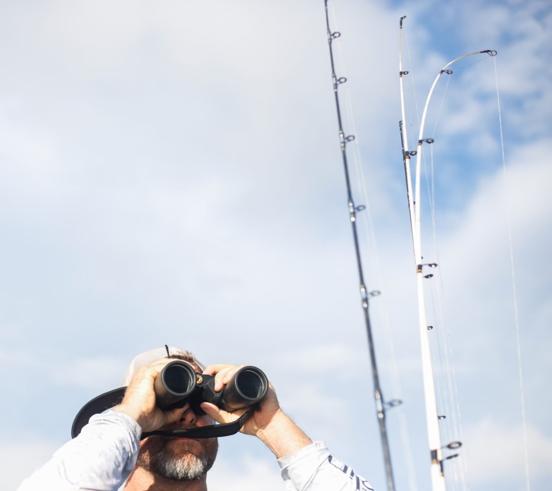 Alex Horton looks through binoculars to try and spot alligators on the surface of the water while hunting on October 26, 2019. (Chris Day/Fresh Take Florida)