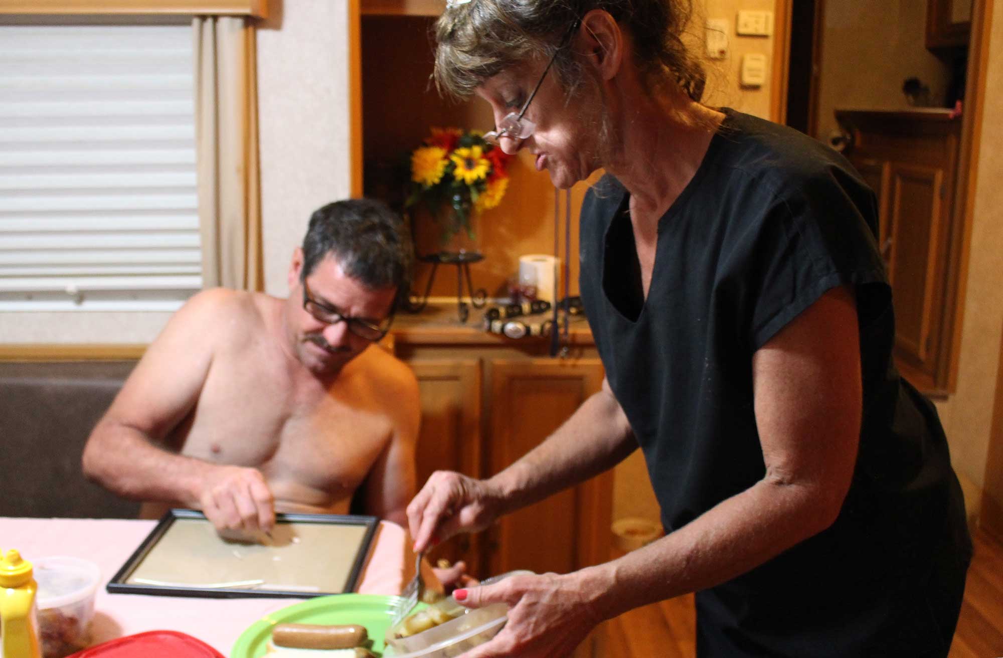 Becky prepares dinner in the camper, as Johnny breaks down heroin for them to share.
